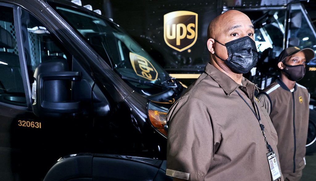 Employees of United Parcel Service (UPS) Joe Jackson (L) and George Clark (R) wait for the arrival of US Secretary of Transportation Pete Buttigieg at a UPS facility that is delivering vaccines to Washington, DC, and Maryland areas March 15, 2021 in Landover, Maryland. (Credit: Alex Wong/Getty Images)