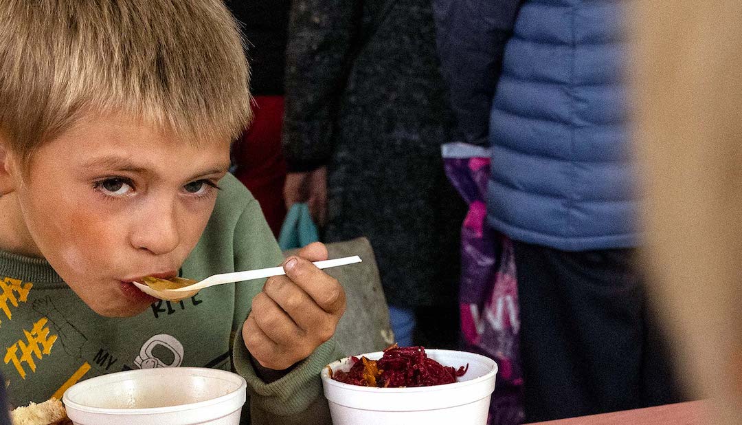 Nikita, 7, eats soup food from Myrne Nebo (Peaceful Heaven) a Ukranian humanitarian organization making hot meals for the needy on October 3, 2022 in Izium, Ukraine. Germany. (Credit: Paula Bronstein/Getty Images)